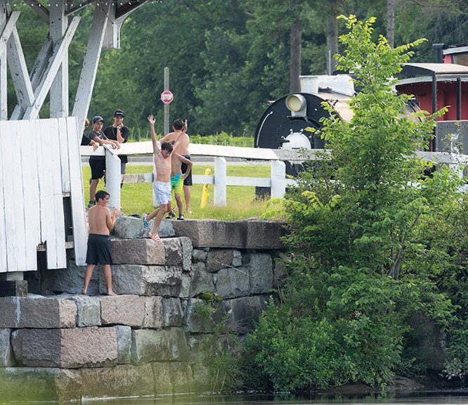 A group of boys jumping into the river from a covered bridge