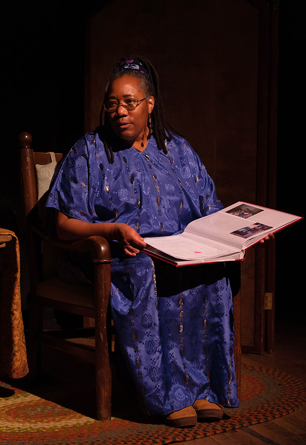 A woman dressed in blue sits reading from a book