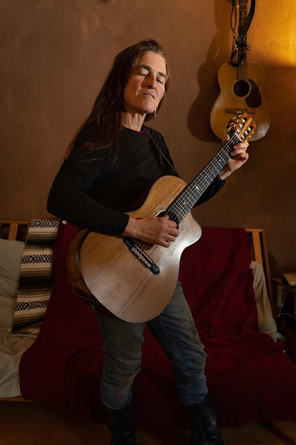 A woman playing guitar indoors
